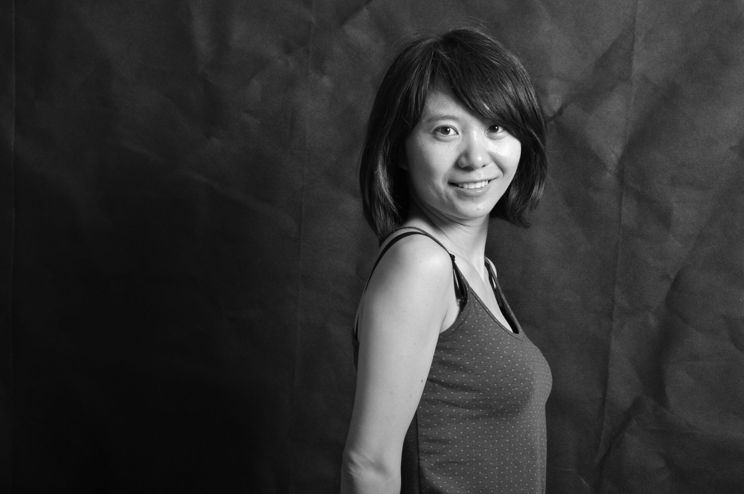 Elegant black and white portrait of a smiling woman in a studio setting.